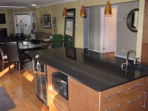 a kitchen with a black counter top next to a dining room table
