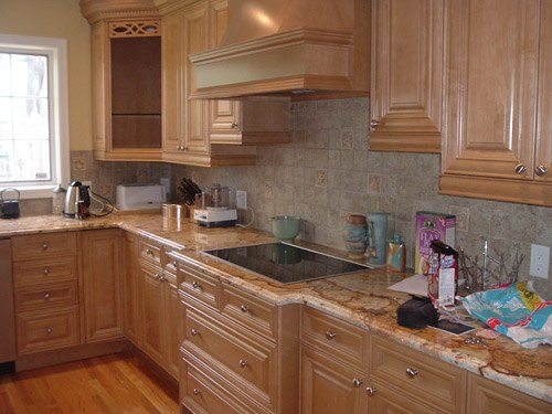 a kitchen with wooden cabinets and marble counter tops