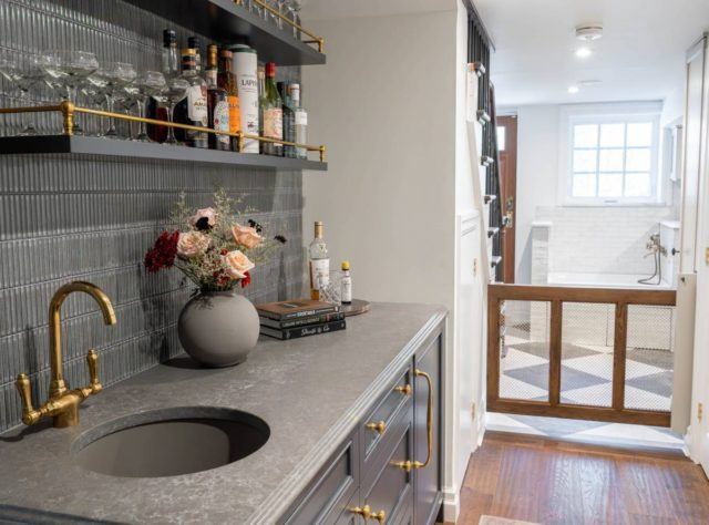 a sink with a gold faucet next to a vase of flowers